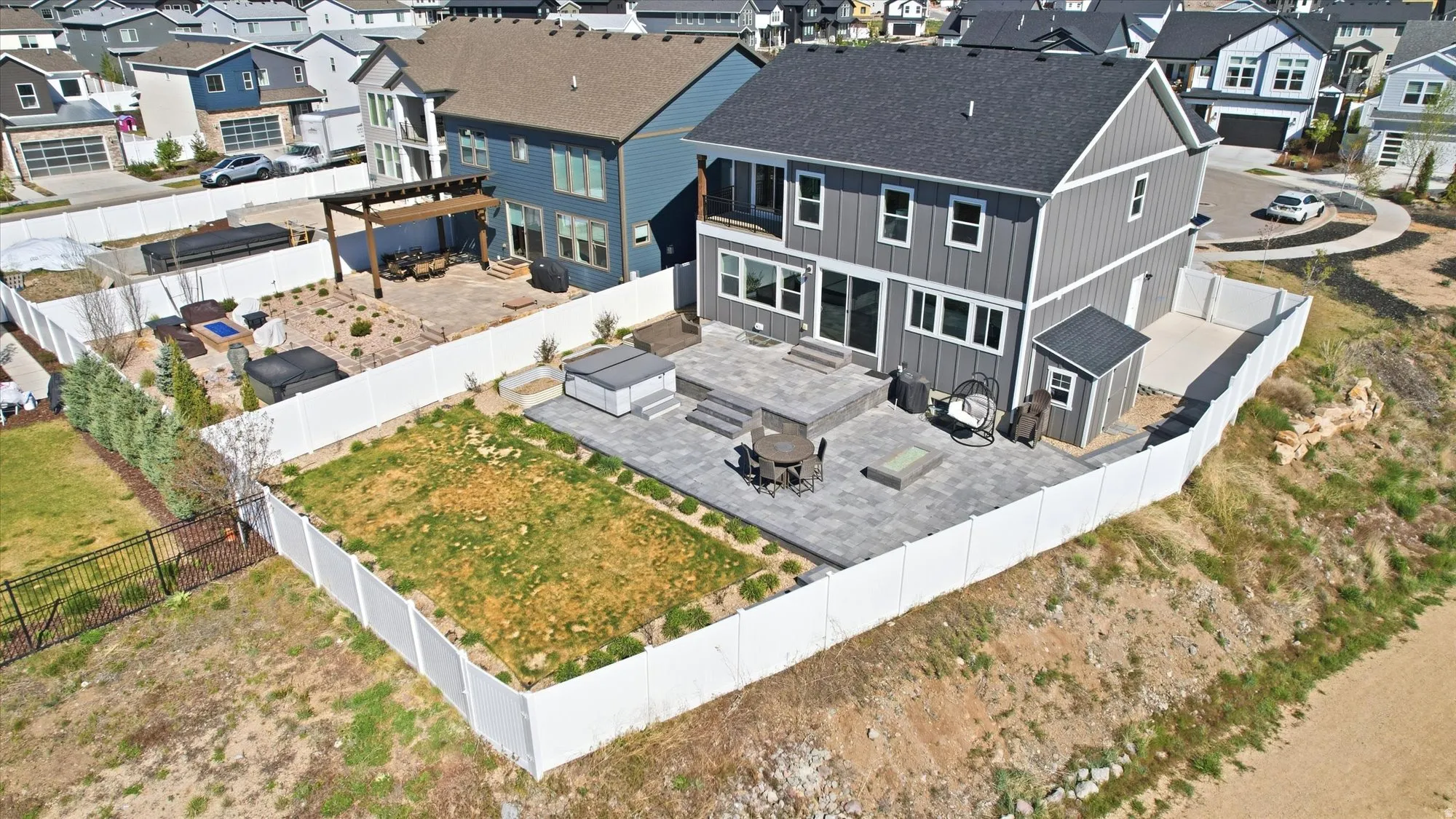 Expansive backyard featuring a large paver patio, a dedicated hot tub area, and a storage shed