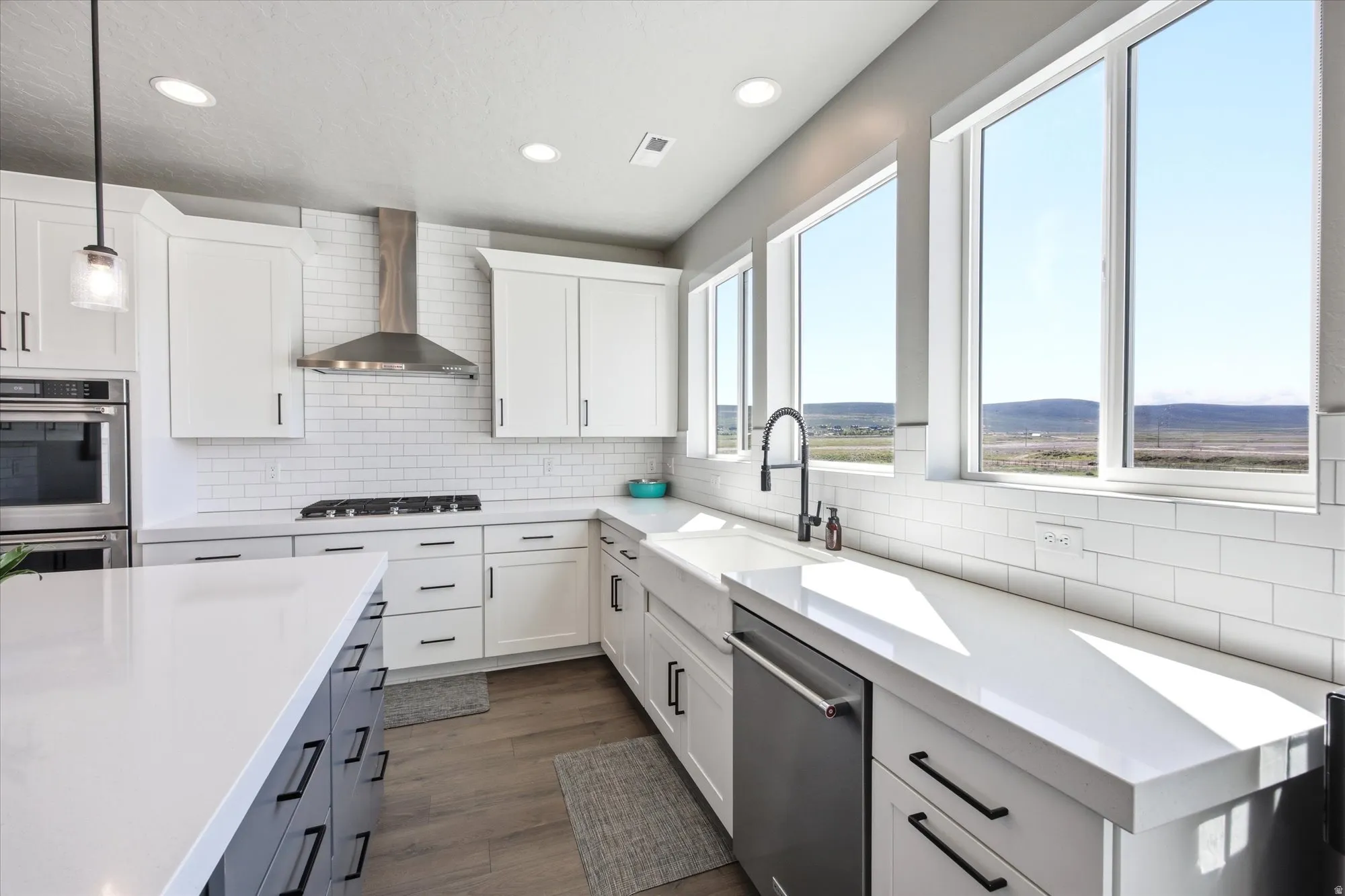 Modern kitchen featuring white shaker cabinetry, white subway tile backsplash, stainless steel appliances, and a central island with contrasting dark cabinetry