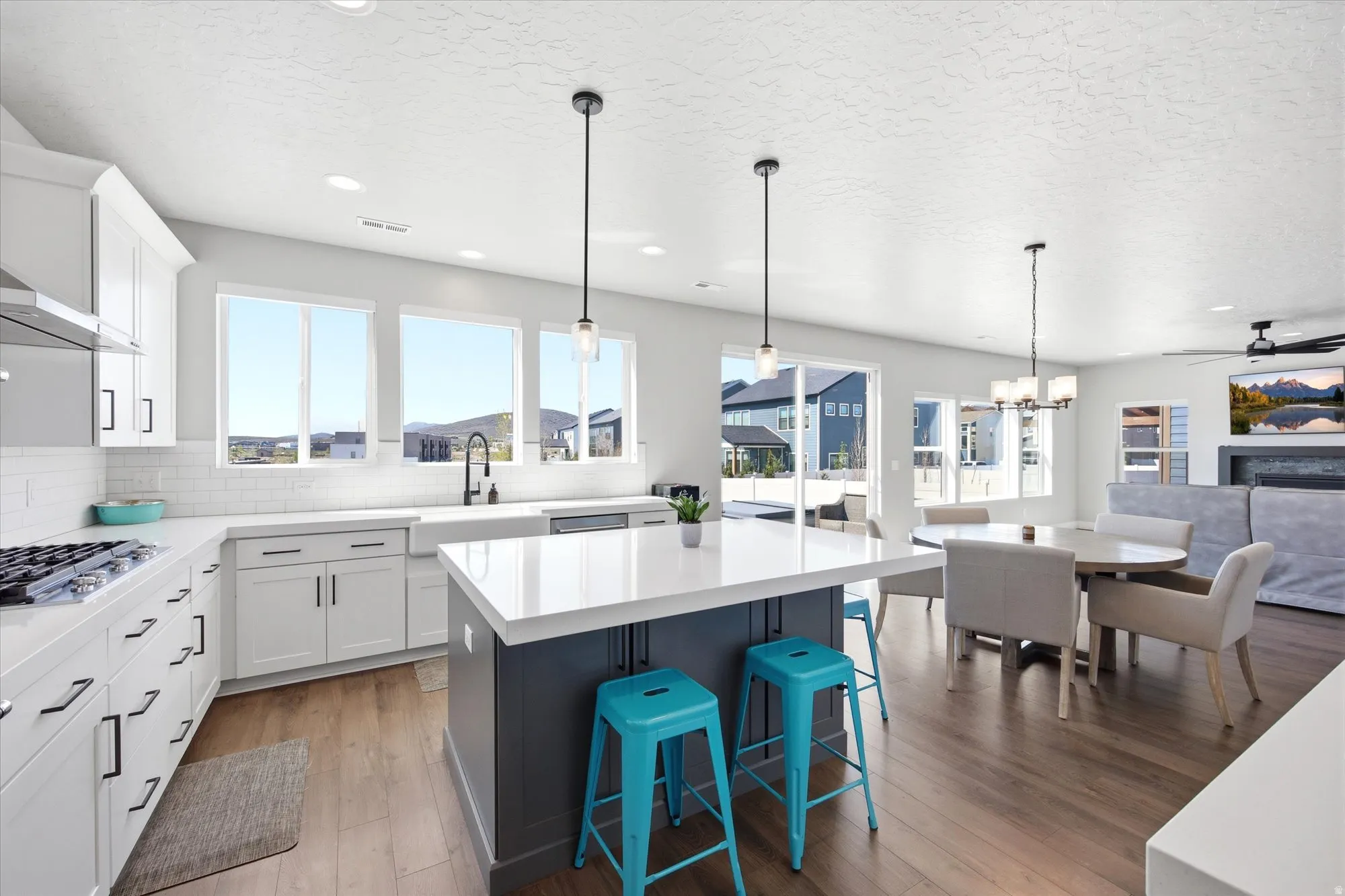 Open-concept kitchen featuring white shaker cabinetry, an island with a contrasting base, and wood-finish flooring