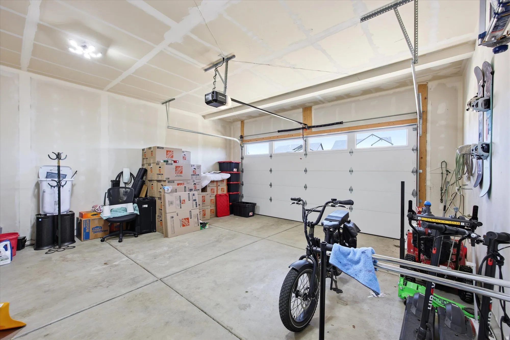 Spacious garage featuring a concrete floor, overhead lighting, and an automatic garage door opener