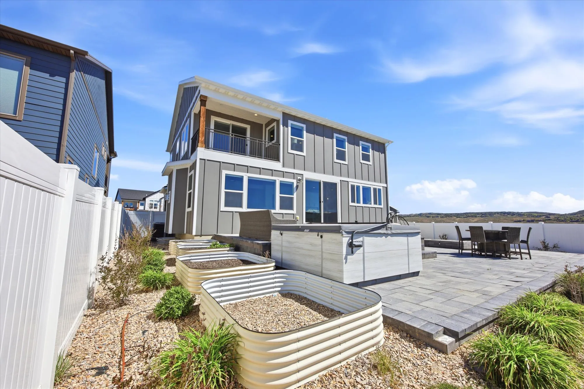 Contemporary exterior with a second-story balcony, a white privacy fence, and a paver patio