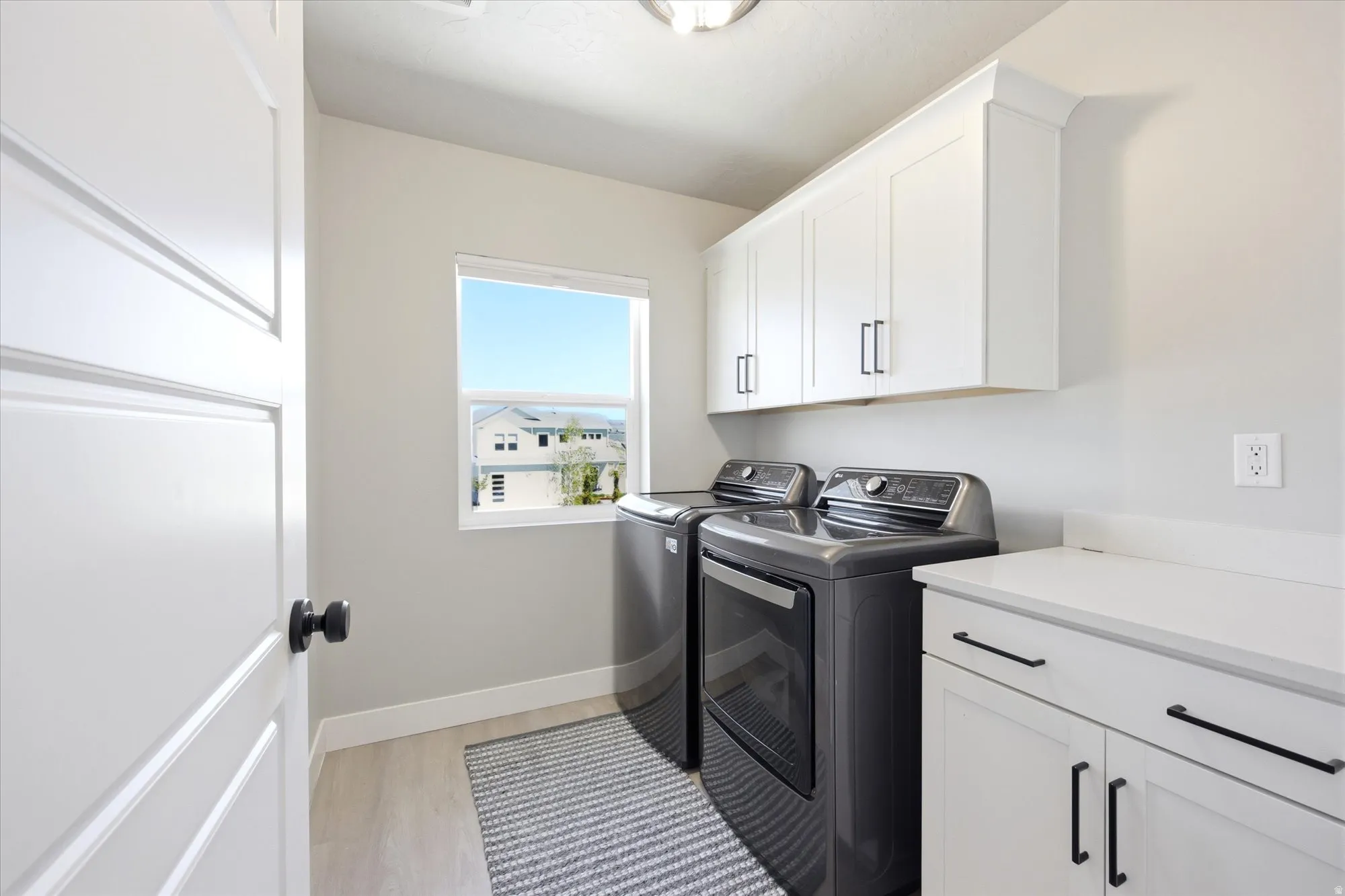 Dedicated laundry area featuring light wood-finish flooring