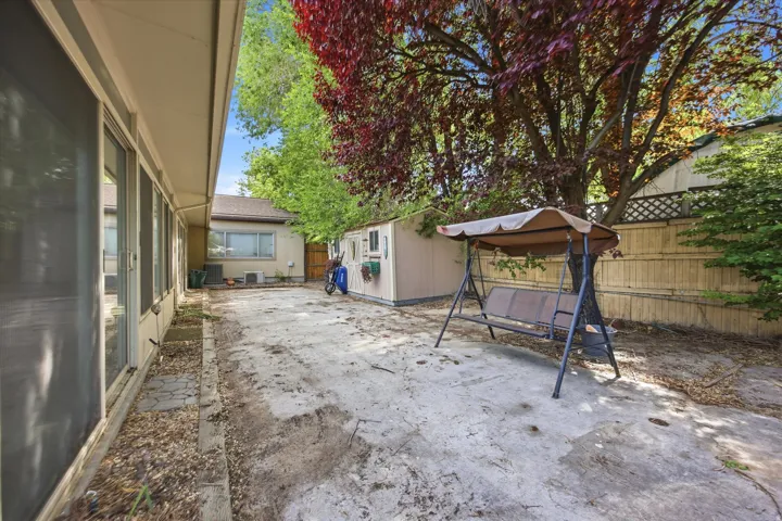 Patio area featuring a mature tree, a privacy fence, and a storage shed