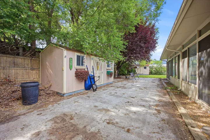 Two storage sheds on concrete pads, surrounded by mature trees and a fenced property line