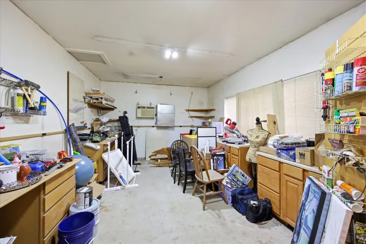 Spacious utility area featuring multiple windows, built-in cabinetry, overhead lighting, and a concrete floor