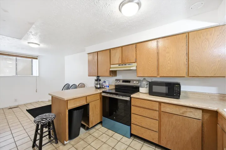 Kitchen with wood cabinetry, light-colored countertops, and tile flooring