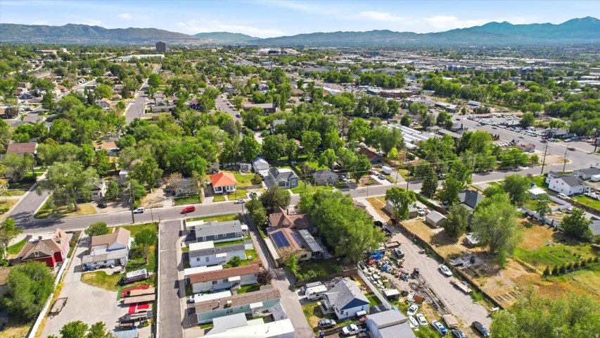 Expansive aerial landscape featuring a residential neighborhood with mature trees, paved streets, and a mountainous backdrop