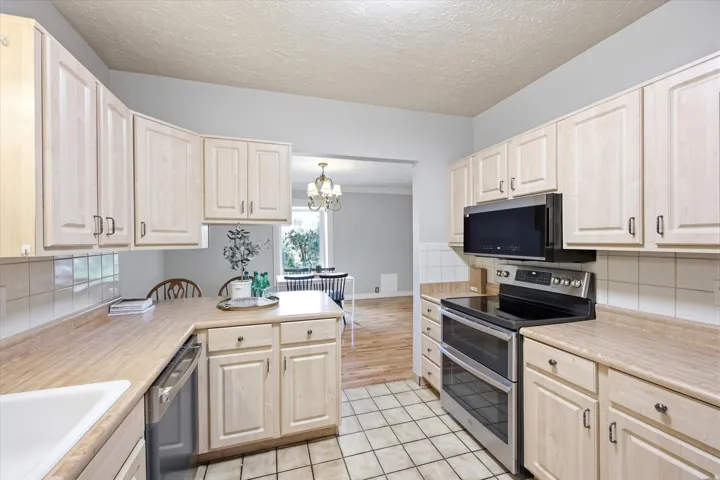 Kitchen featuring light wood-finish cabinetry, tile flooring, and integrated stainless steel appliances