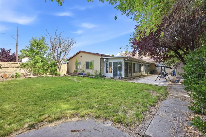 Expansive backyard featuring a large grass lawn, mature trees, and a concrete patio
