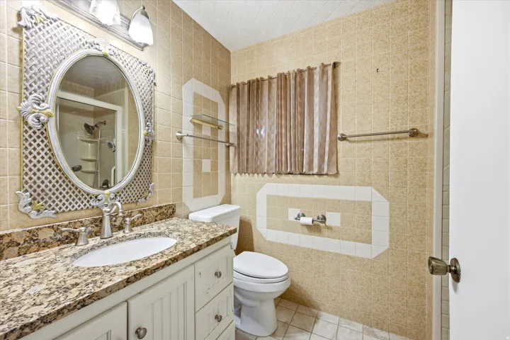 Bathroom featuring a vanity with a patterned countertop, a white sink, and a decorative oval mirror