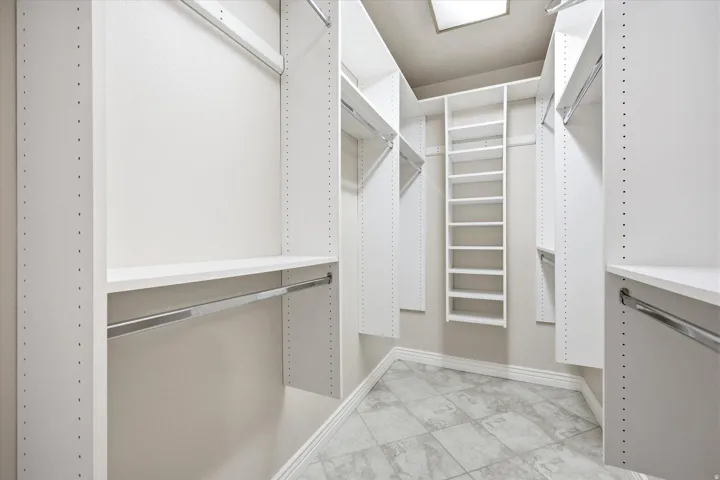 Custom closet system featuring multiple hanging rods, adjustable shelving, integrated shoe rack, and square ceiling light fixture