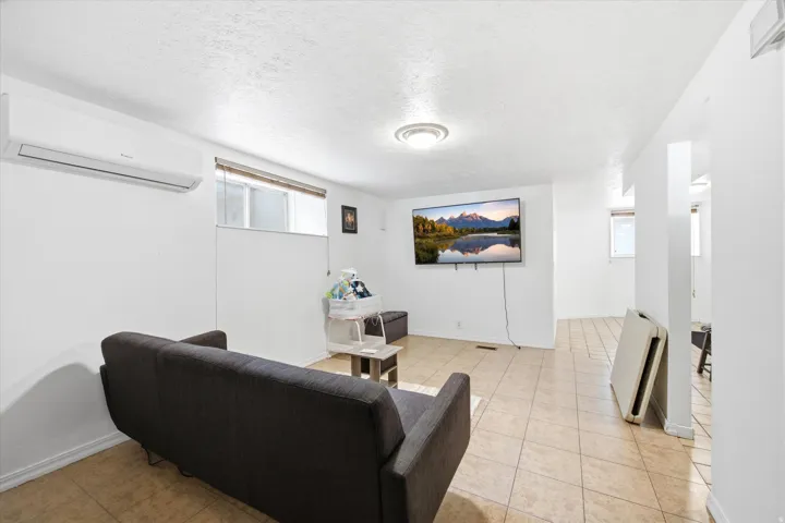 Spacious room featuring neutral-toned tile flooring, white walls, and a mini-split air conditioning unit