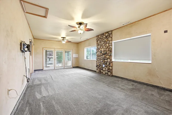 Spacious room featuring neutral carpeting, a stone accent wall, and multiple windows