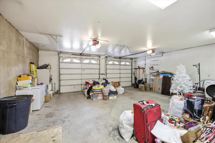 Two-car garage featuring a concrete floor, two sectional garage doors, overhead lighting, and a skylight