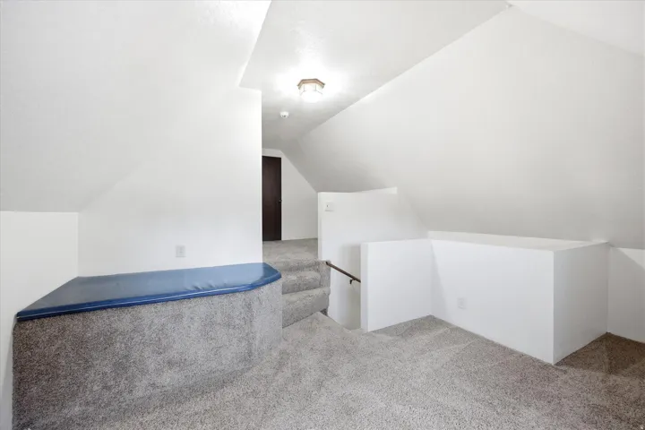 Carpeted upper level with sloped ceilings, a built-in upholstered seating area, and a recessed ceiling light fixture