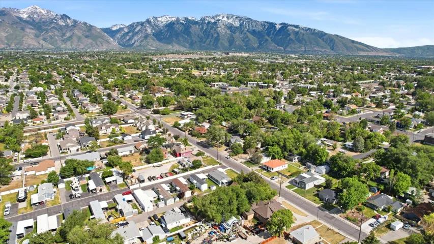 Expansive neighborhood setting featuring a mix of residential properties, mature trees, and a distant mountain range with snow-capped peaks