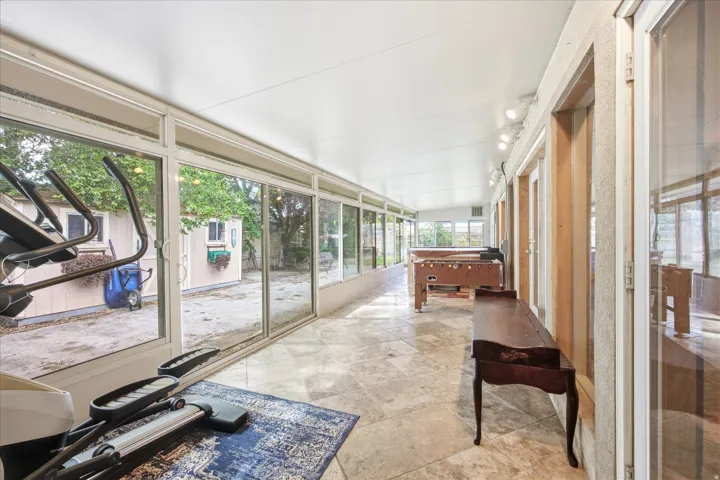 Spacious sunroom featuring extensive glass panels, a tiled floor, and a recessed ceiling with track lighting