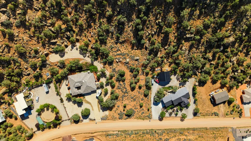 Aerial property view featuring two residential structures with surrounding natural arid landscape and vegetation