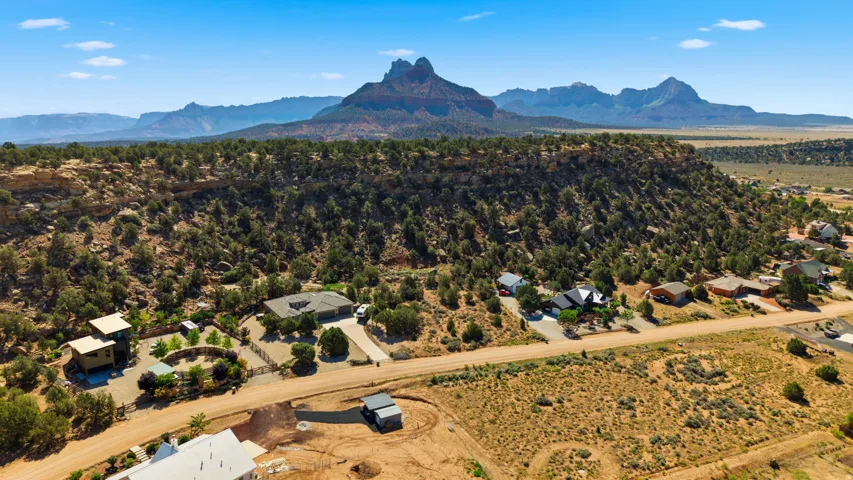 Aerial perspective showcasing multiple properties nestled against a natural, rocky hillside with abundant green shrubbery