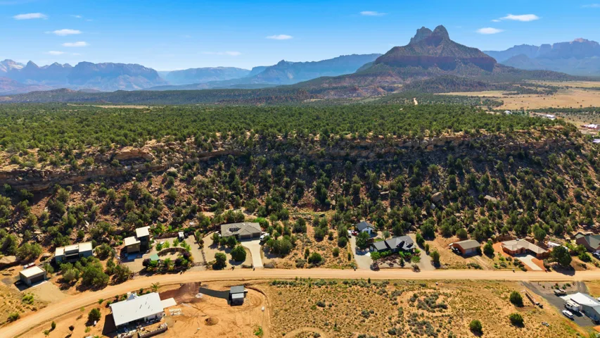 Aerial perspective showcasing multiple properties situated on desert terrain with prominent mountainous backdrops