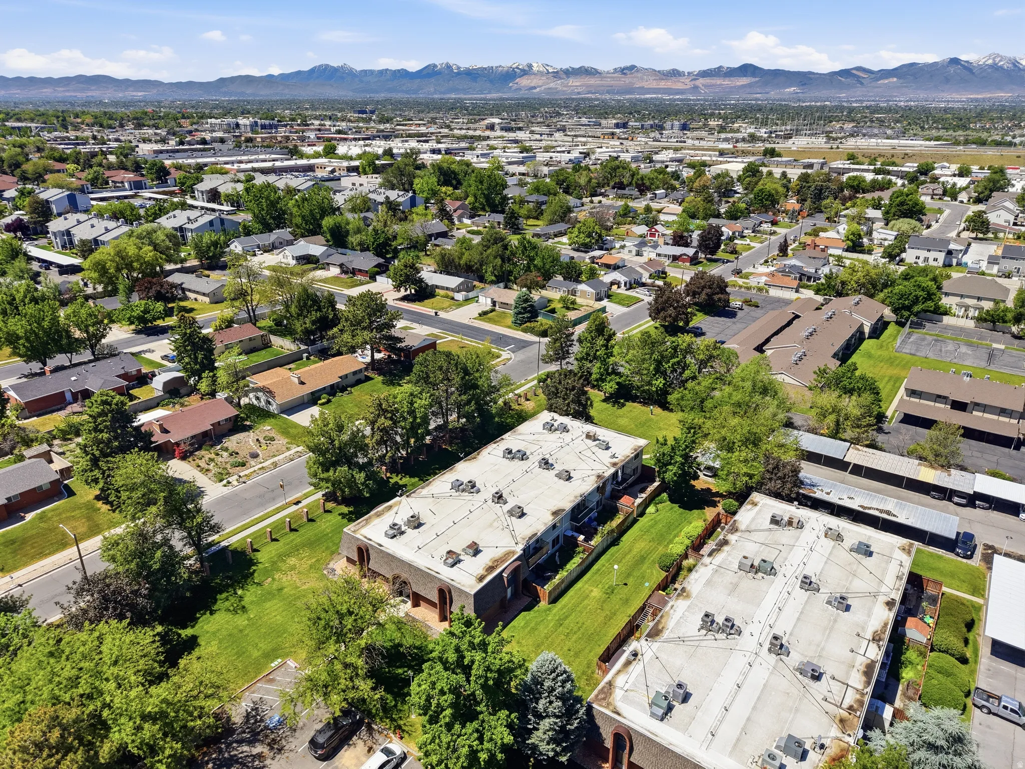 Aerial perspective showcasing multi-unit residential buildings with flat roofs, multiple rooftop HVAC units, and surrounding green spaces