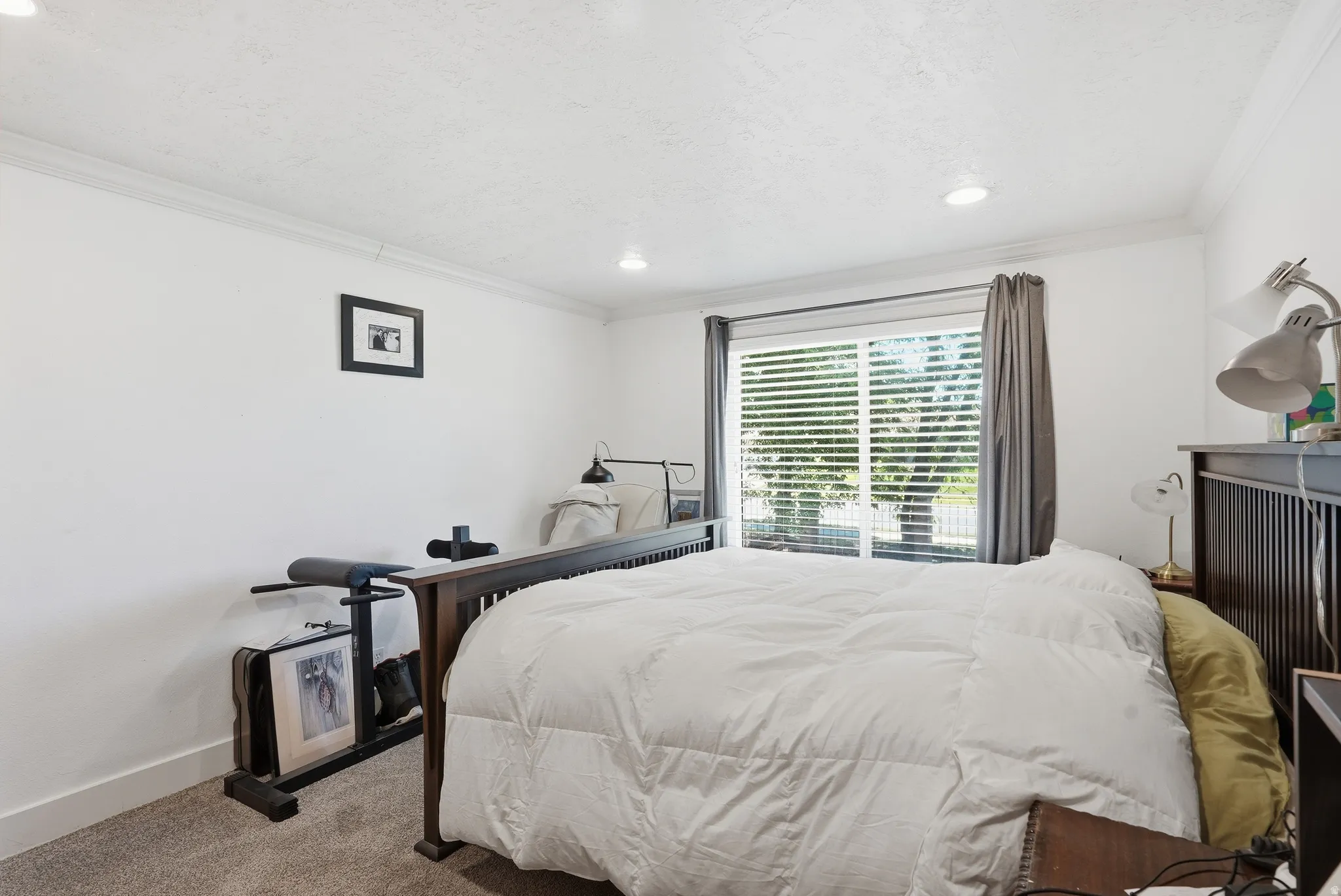 Carpeted room featuring a large window with blinds and dark drapery, recessed lighting, and crown molding
