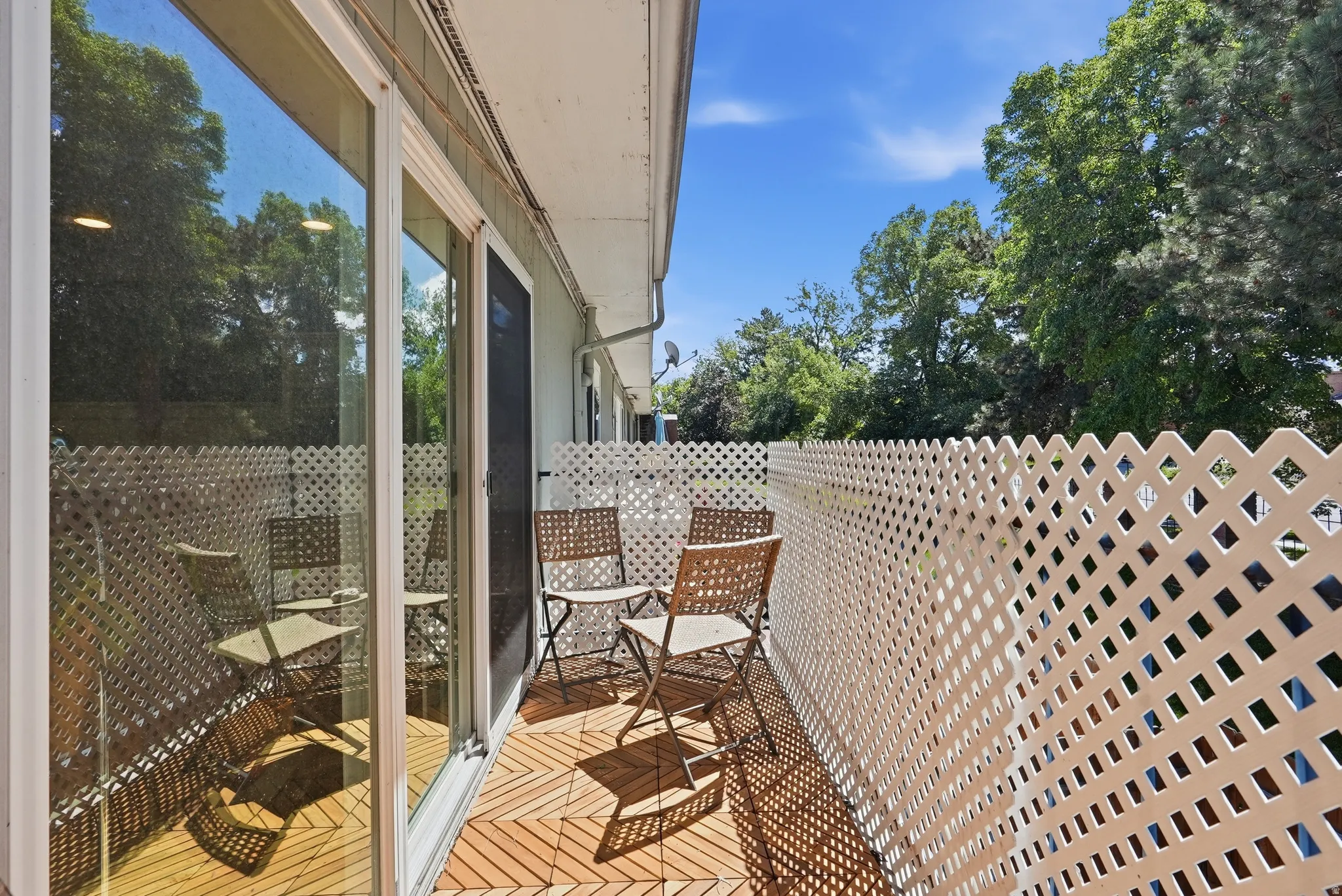 Private outdoor balcony featuring wood-look tile flooring and a lattice privacy screen