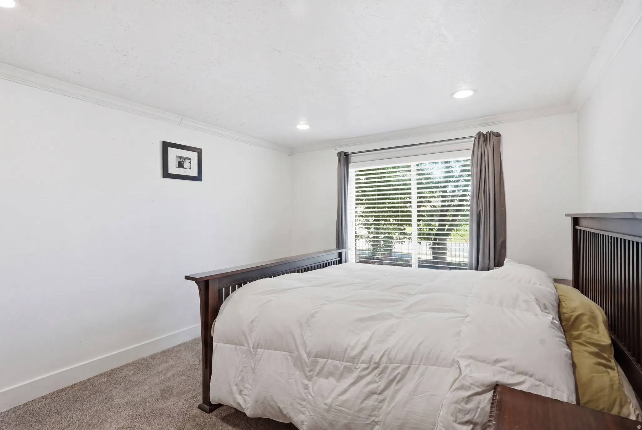 Bright room featuring a large window with blinds and curtains, recessed lighting, crown molding, and carpeted flooring