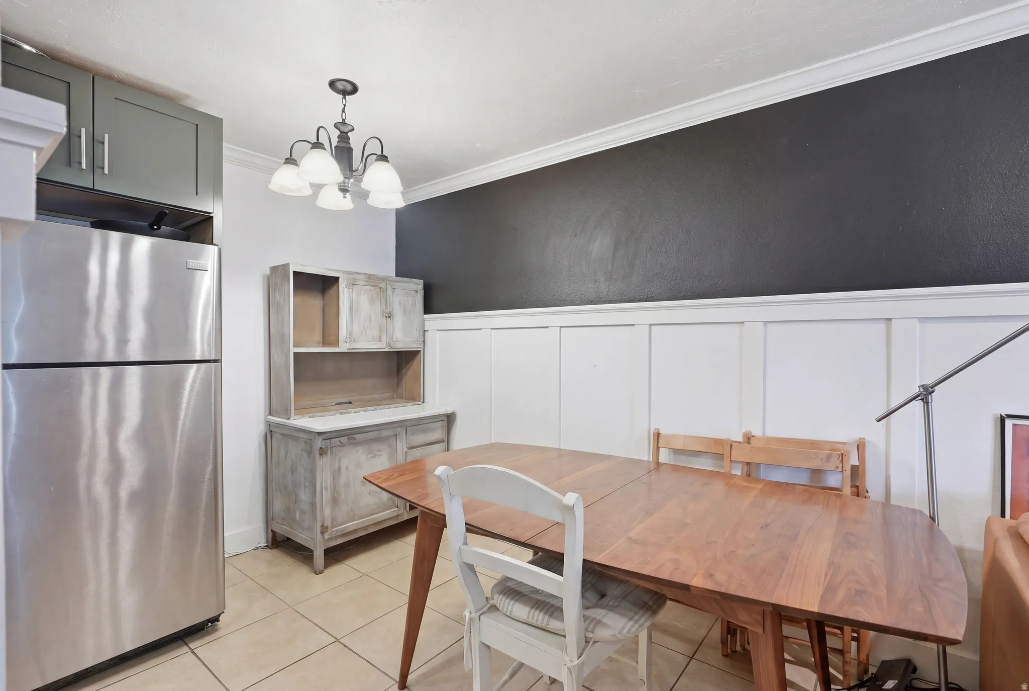 Dining area featuring wainscoting, crown molding, and tiled flooring