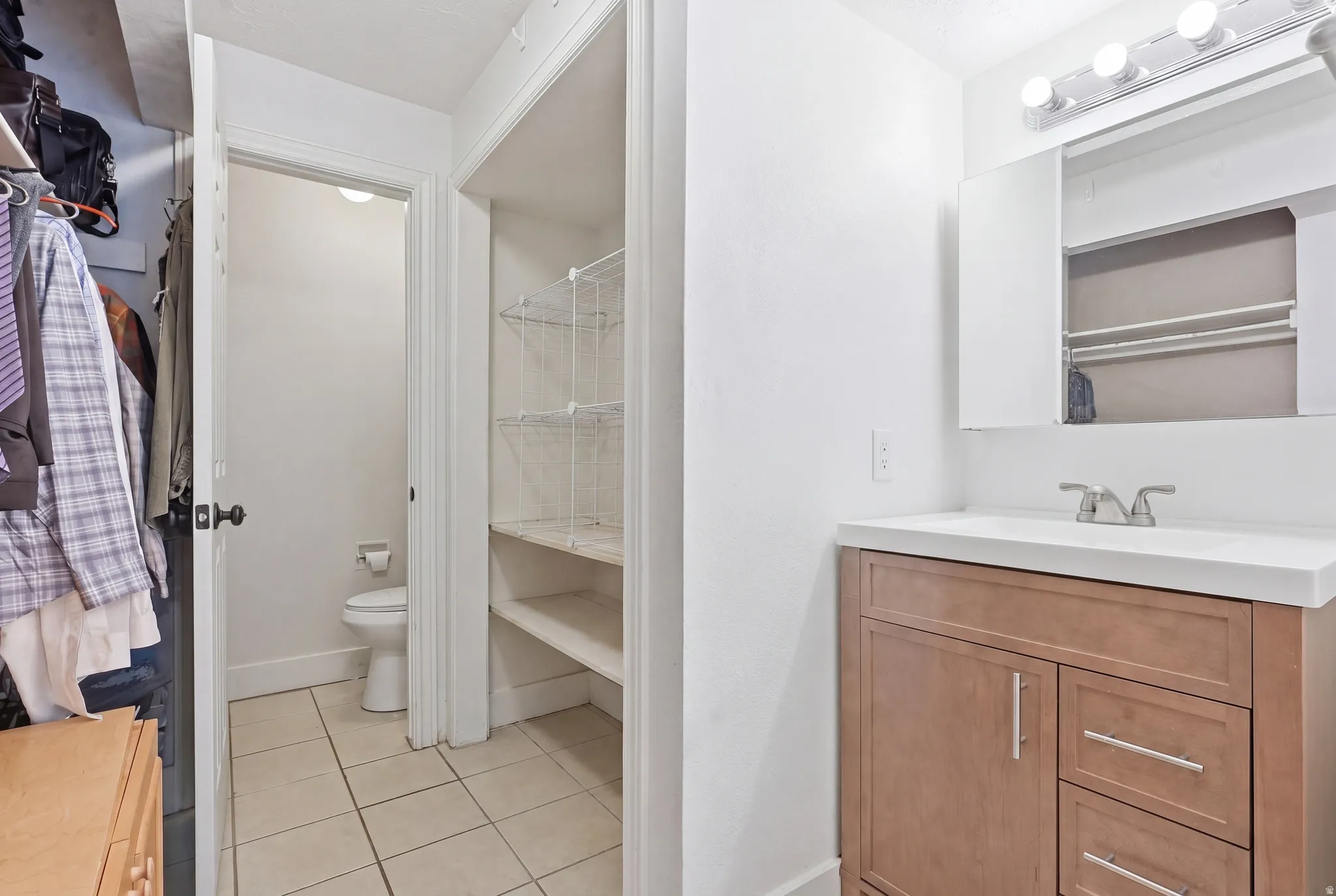 Bathroom vanity with wood-finish cabinetry, a white countertop, and a chrome faucet