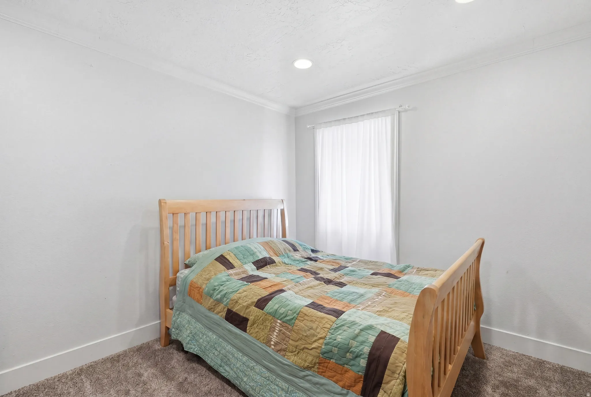 Bedroom featuring light neutral wall paint and a window with sheer white curtains