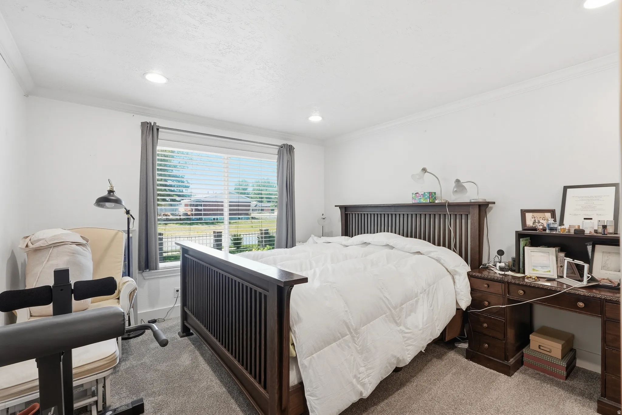 Bright room featuring a large window with blinds, recessed lighting, crown molding, and carpeted flooring