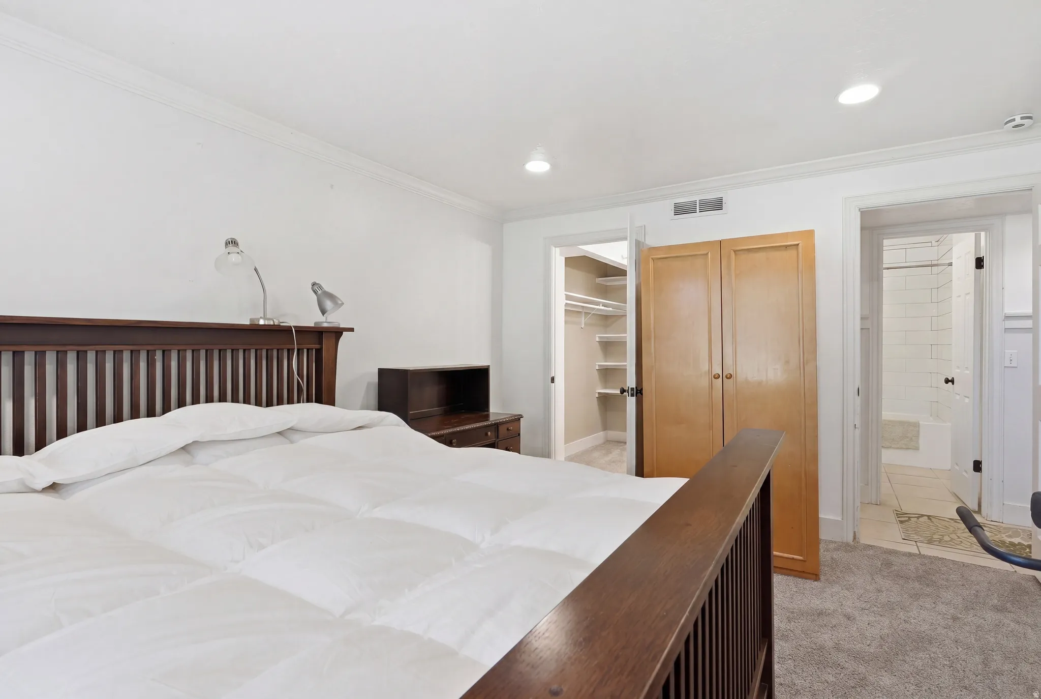 Bedroom featuring plush carpet flooring, recessed lighting, crown molding, and an open doorway leading to a walk-in closet with shelving