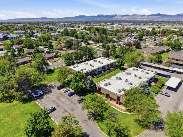 Aerial perspective showcasing two multi-unit buildings with flat roofs, surrounded by mature trees and manicured green spaces