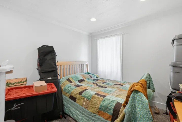 Bright room featuring a window with white blinds, recessed lighting, crown molding, and light gray wall paint