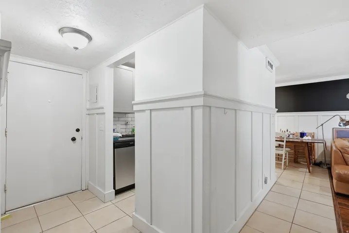 Entryway featuring ceramic tile flooring, a white paneled door, and wainscoting