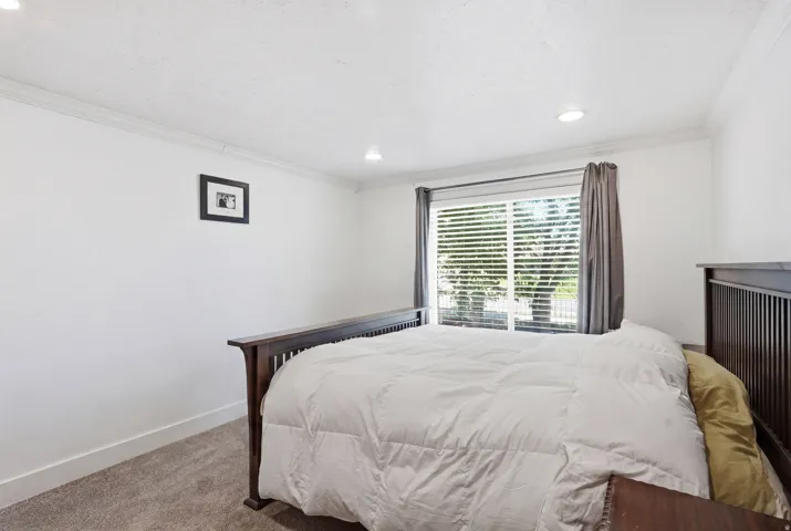 Bright room featuring a large window with blinds and curtains, recessed lighting, crown molding, and carpeted flooring