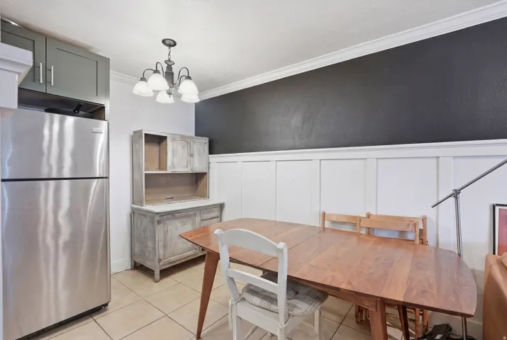 Dining area featuring wainscoting, crown molding, and tiled flooring