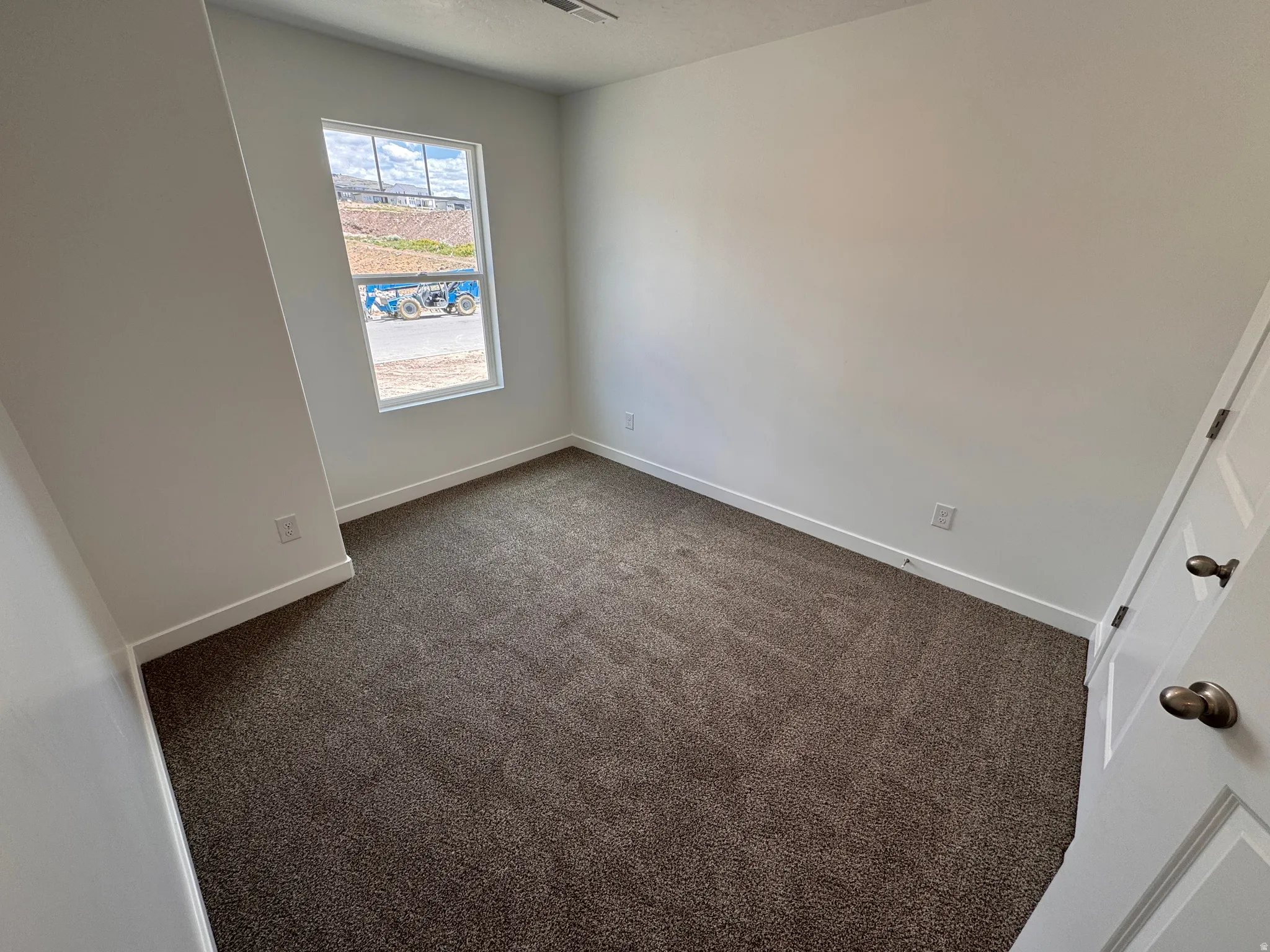 Carpeted interior space featuring a window with white trim, white walls, and white baseboards