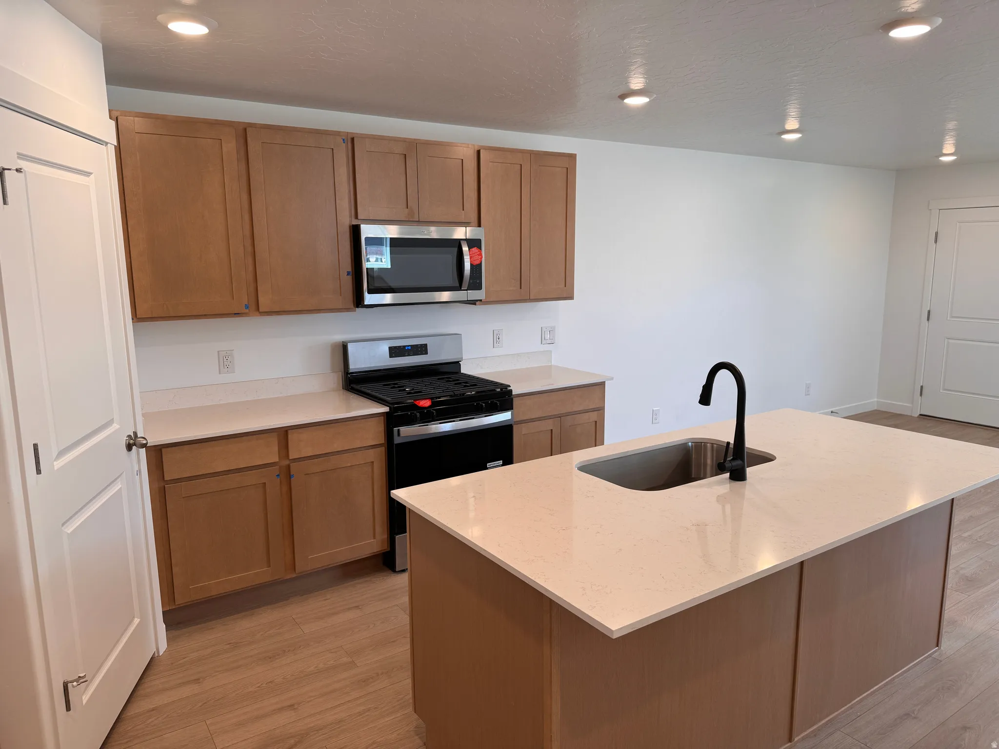 Modern kitchen featuring light wood-finish cabinetry, light-toned countertops, and stainless steel appliances