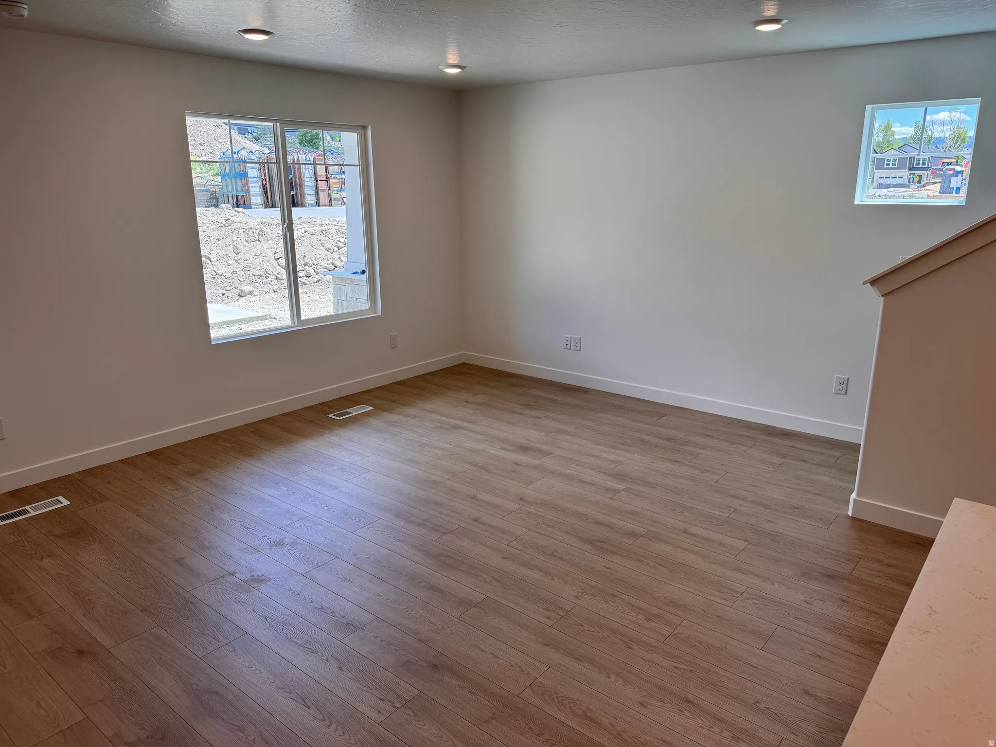 Spacious room featuring wood-finish flooring, recessed lighting, and white baseboards