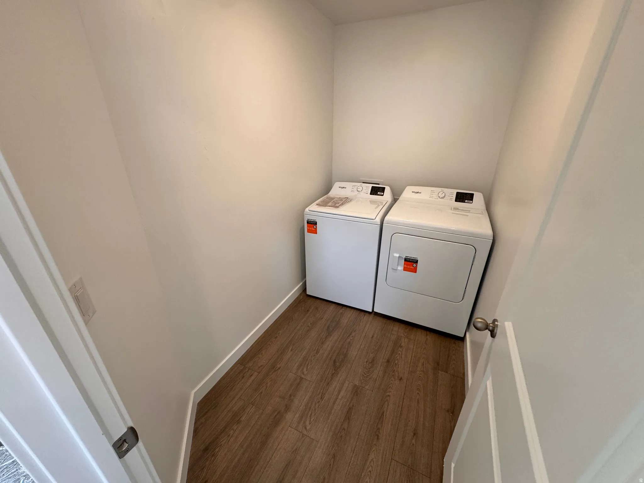 Dedicated laundry area featuring wood-finish flooring and crisp white walls