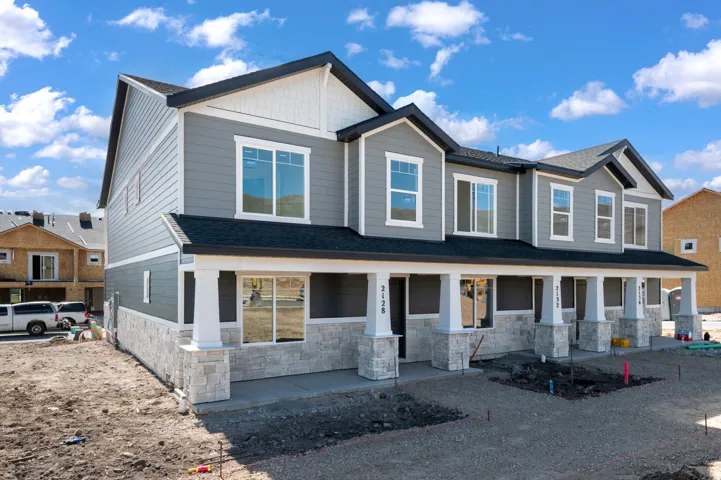 Modern townhome exterior featuring grey siding and white stone veneer