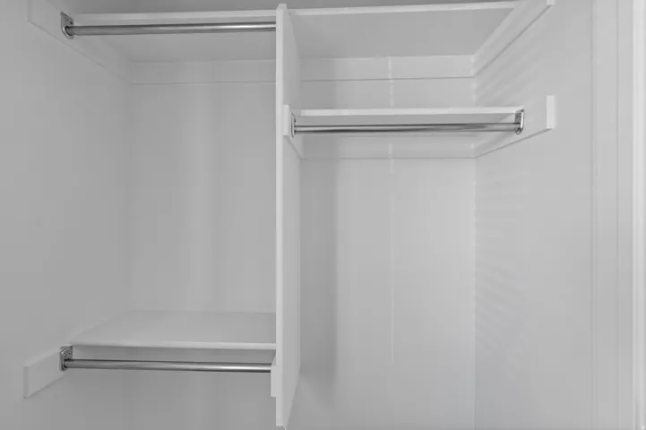 Built-in closet system featuring white shelving and chrome hanging rods