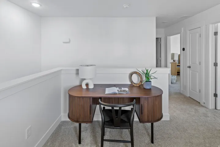 Carpeted loft area featuring a half-wall railing, recessed lighting, and white walls
