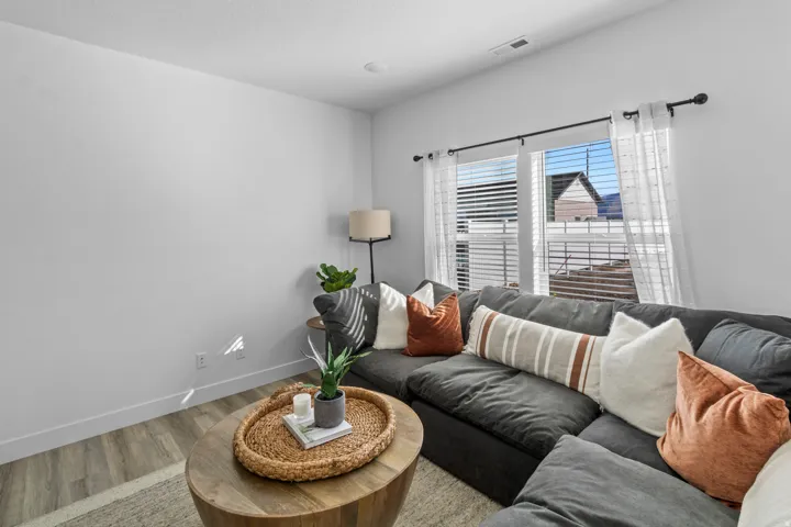Spacious living area featuring light wood-finish flooring, white baseboards, and bright white walls