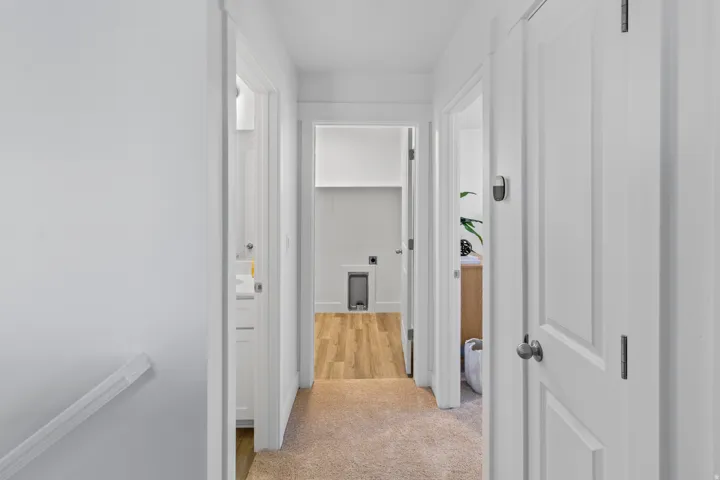 Hallway featuring neutral carpet, white trim, and multiple doorways