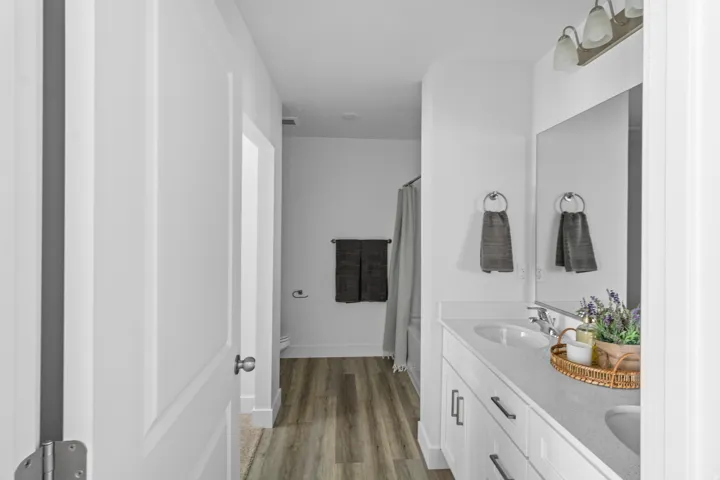 Bathroom featuring a double vanity with stone countertops, integrated sinks, and white shaker-style cabinetry