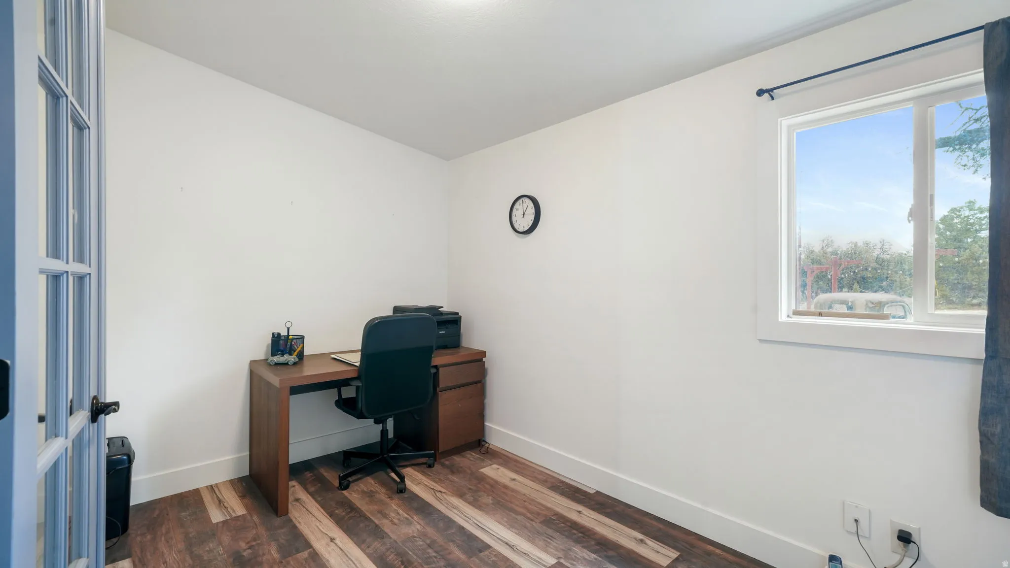 Bright room featuring wood-finish flooring, white walls, and a large window