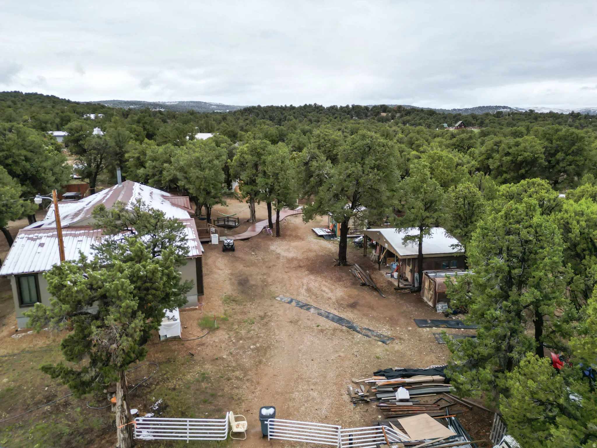 Expansive wooded property featuring two detached structures with metal roofing